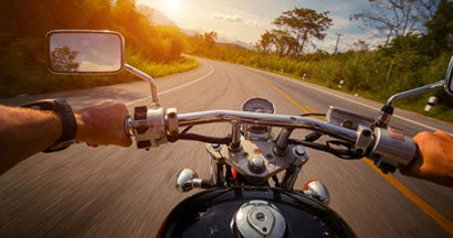 Motorcyclist riding a motorcycle through a sunset. 