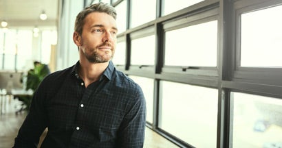 mature businessman standing in the office with his colleagues in the background