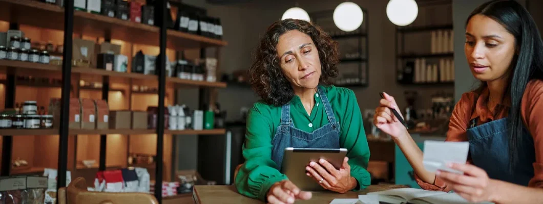 Manager and an employee going over receipts at a table. How to Get a Mortgage As a Self-Employed Business Owner.