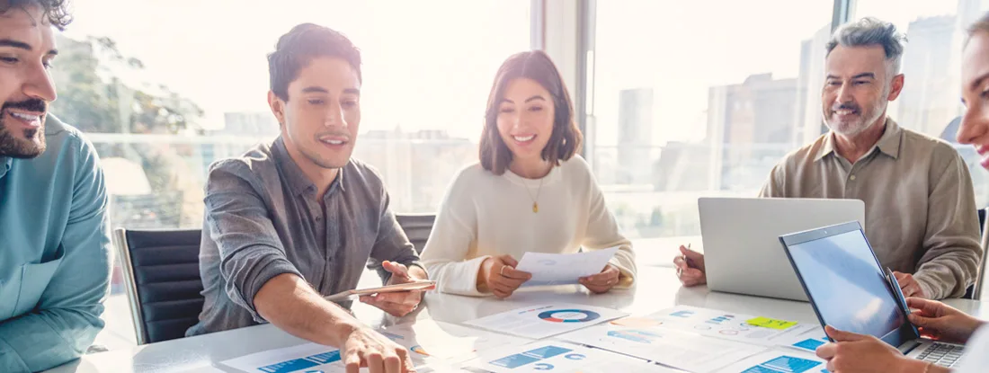 Group of co-workers working on a board room table at a business presentation. Find Palo Alto business insurance.