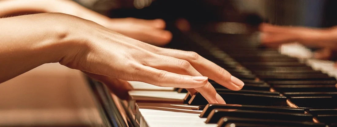 Close up view of female hands playing piano. Find Body Part Insurance.