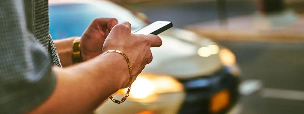 Man using phone standing near car. How to Find the Best Car Insurance Coverage in Great Neck, New York.