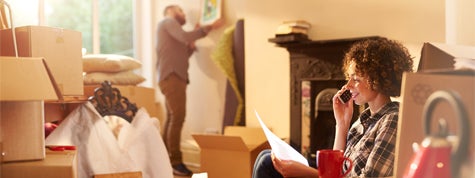 a couple move into their new home while woman talks on the phone whilst referring to a mortgage gift letter that she is holding