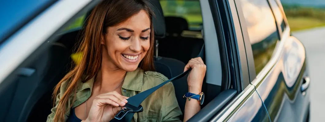Business woman sitting in a car putting on her seat belt. How to Find the Best Car Insurance in Bixby, OK.