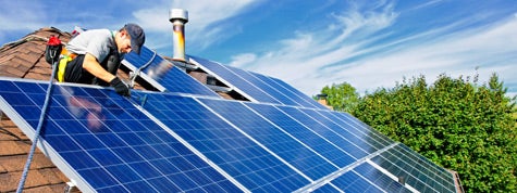 Man installing alternative energy photovoltaic solar panels on roof