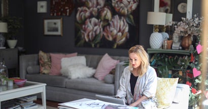 Woman checking her emails on the sofa at home. Find Fine Art Insurance.