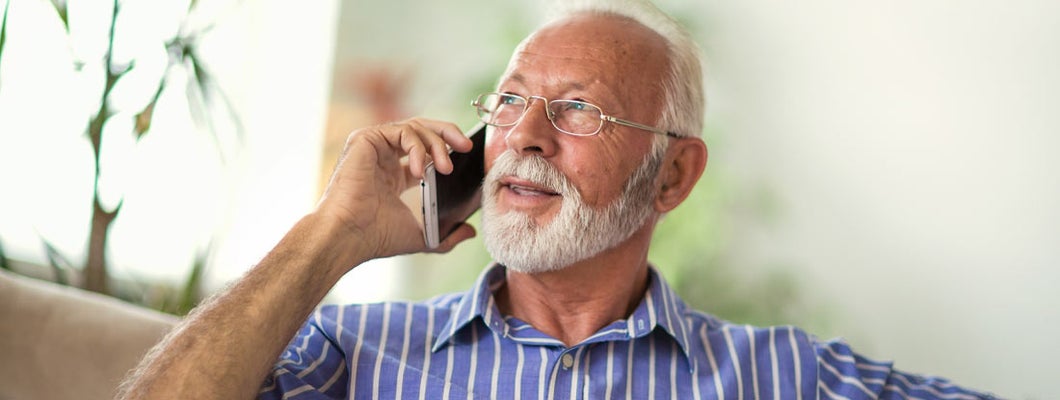 Senior man chatting on a mobile phone at home. Find Current Annuity Rates.