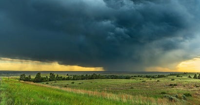 Weather supercell passes over a grassy part of the Great Plains while forming a tornado. Find Tornado Insurance.