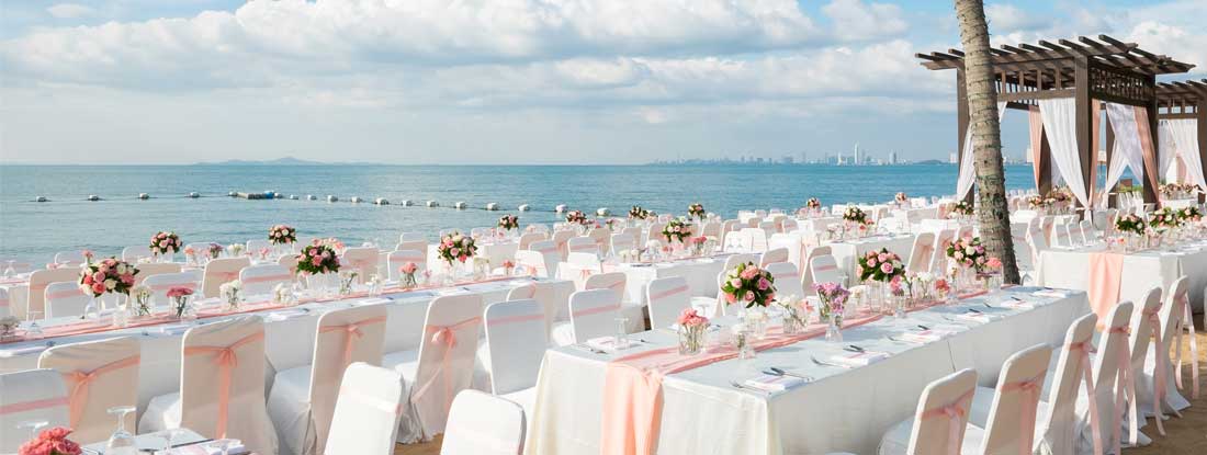 Wedding ceremony on the beach with rental tables and chairs. Find Wedding Event Insurance.