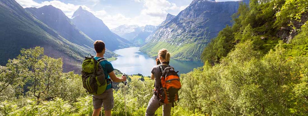 Two hikers at viewpoint in mountains with lake, sunny summer.  Find cheap life insurance. 
