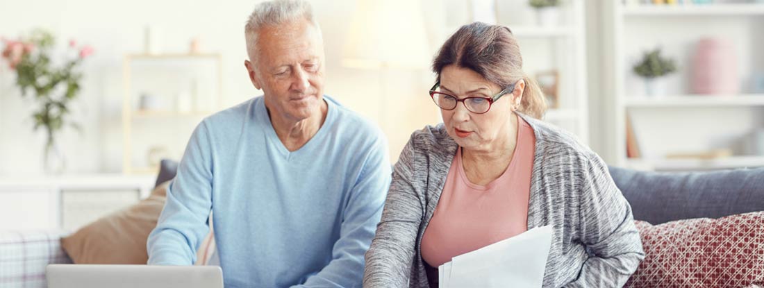 Couple reviewing documents and using a laptop. Non-qualified variable annuities and taxes.