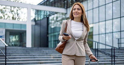 Woman in business attire holding smartphone. Business Insurance FAQs. 