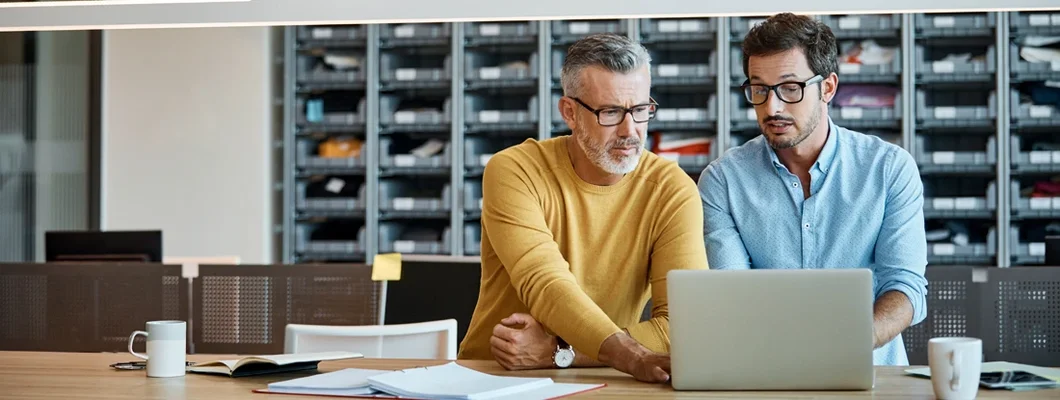 Businessmen using laptop together at desk. College Grove, Tennessee Business Insurance.