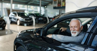 Senior man inside of a car in a showroom. How Much Car Insurance Do I Need?