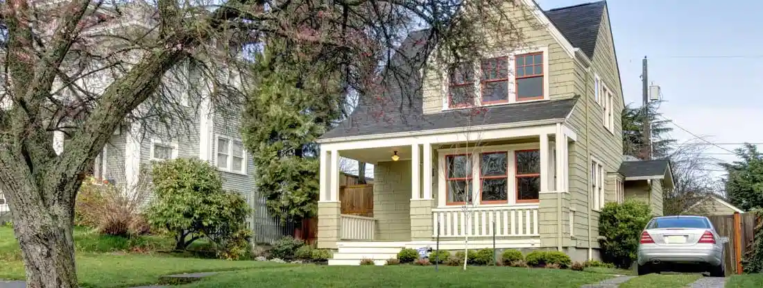 Two story home in residential neighborhood on a sunny day. Get Umbrella Insurance Quotes.
