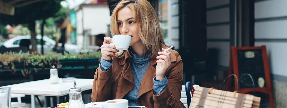 Woman smoking at a cafe. Smokers Life Insurance.