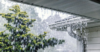 Downpour rain water overflowing over the overhanging eaves of gutter system. Gutter Floods.