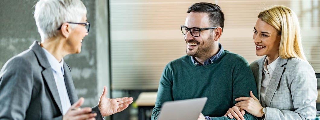 Happy couple talking to their insurance agent in the office. Your free guide to all the insurance that matters.