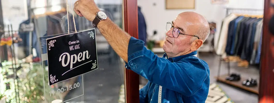 Professional tailor putting an open sign on tailoring store door. Find Laramie, Wyoming business insurance. 