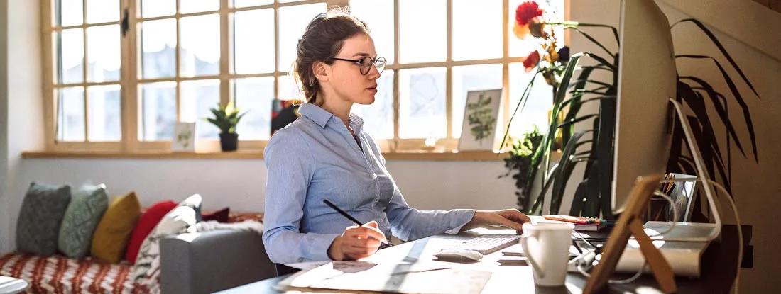 Woman working from a bright home office setup. Do You Need Business Insurance If You Run a Freelance LLC out of Your Home?