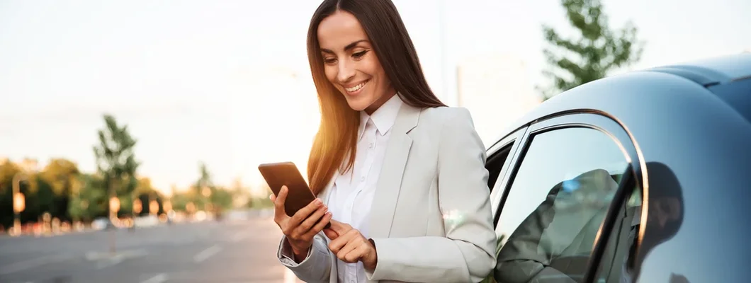 Woman using her smart phone while standing near modern car outdoors. How to Find the Best Car Insurance Policy in Chesterfield, Missouri.