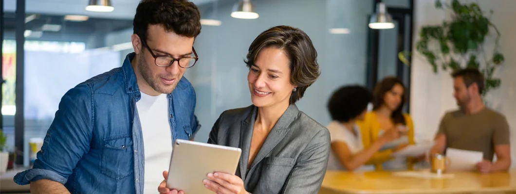 Coworkers working together at the office looking at documents on a tablet. Experts break down Herndon, VA business insurance costs, coverage, companies, and more.