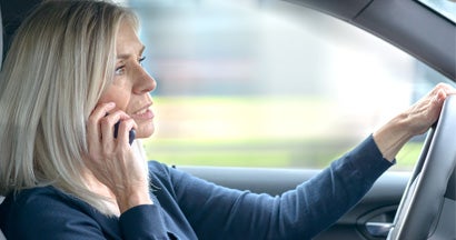 Parent driver chatting on her mobile in the car as she drives through town