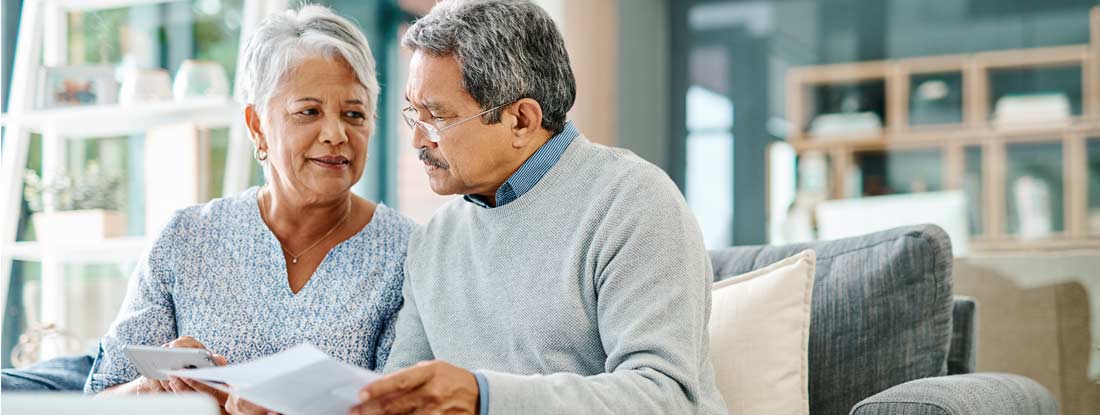 Mature couple going through paperwork together at home. How to buy long term care insurance.