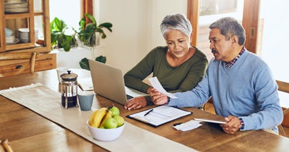 Senior couple using a laptop together at home. Long term care insurance benefits.