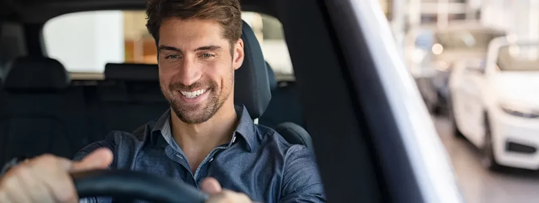 Man examining a new car in a showroom. How to Find the Best Car Insurance in Essex, Vermont.