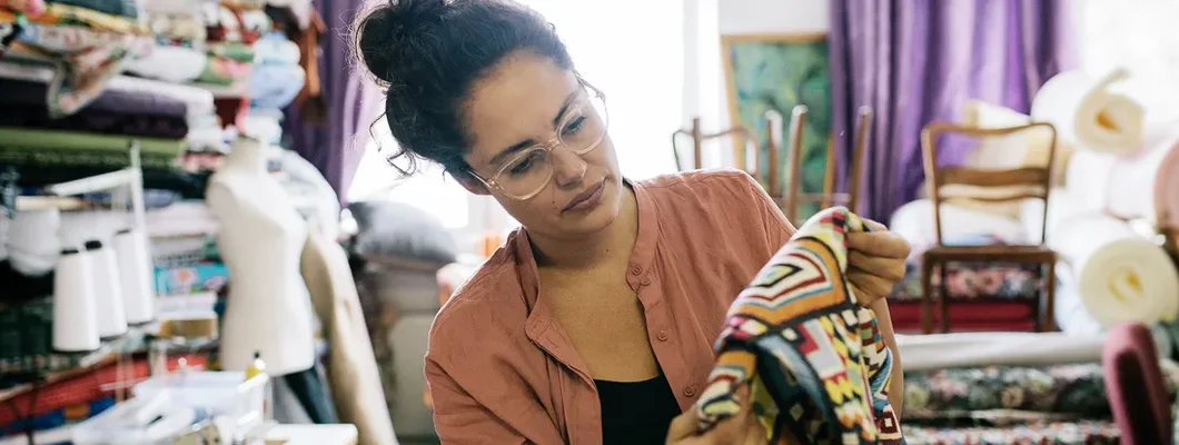 Craftswoman Examining Colorful Fabric In Workshop. Chesterfield, Missouri Business Insurance. 