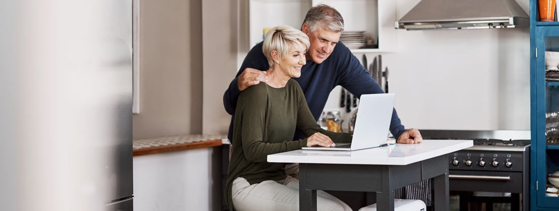 Mature couple browsing fixed annuities on a laptop at home. Find Fixed Annuities. 