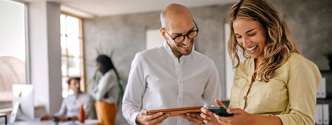 Businessman and businesswoman smiling looking at phone. Find Georgia Landlord Insurance.
