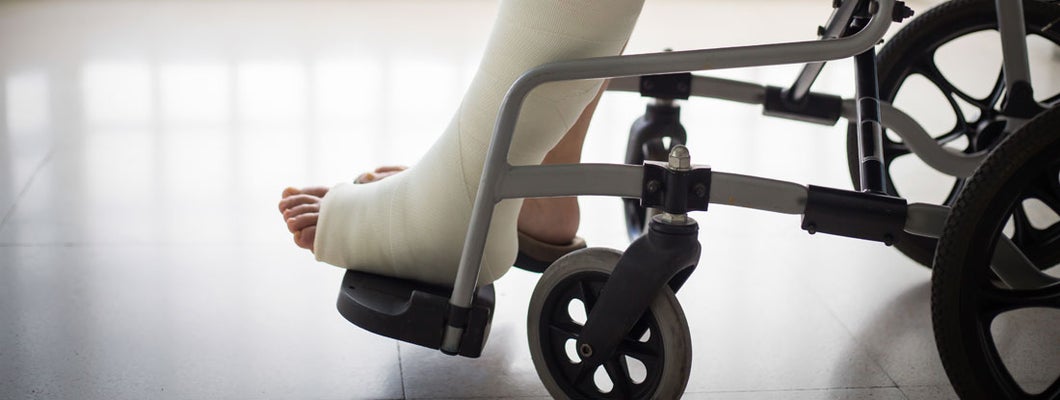 Adult leg injury sitting on wheelchair with plaster foot. Best Group Short Term Disability Insurance.