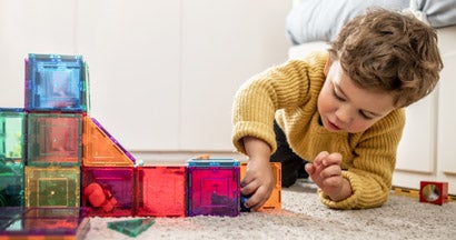 Child playing with magnetic bright multicolored tiles. Find daycare insurance.