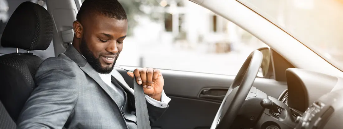 Businessman fastening seat belt in his car. Find Irvine, California car insurance.