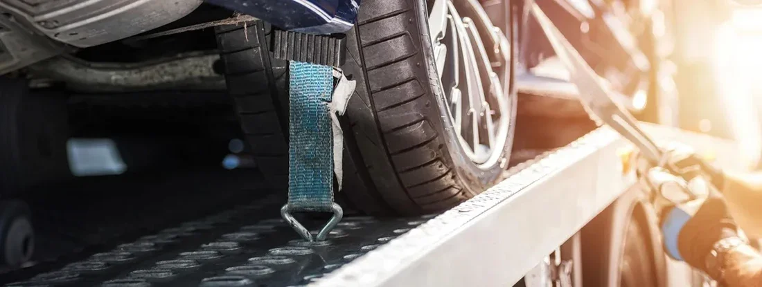 Towing operator managing vehicle on flatbed truck. What Is Towing and Roadside Assistance Coverage?