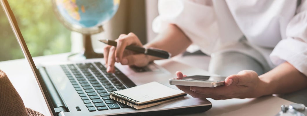 Travel agent planning vacation trip and searching information on laptop. Find Travel Agency Insurance.