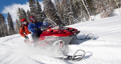 Couple Sitting on Snowmobile. Snowmobile Insurance 101.