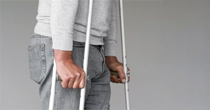 Man on crutches on a gray background. Disability income insurance programs in my state.
