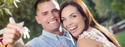 A man and woman holding up the keys to their new home.