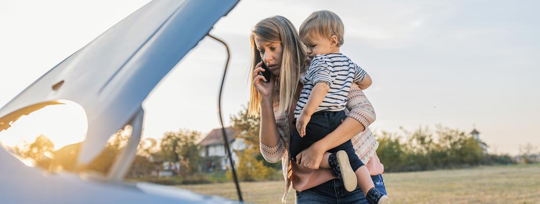 Woman standing by broken down car and waiting for assistance. Lockout and Dead Battery Service.