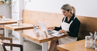 Cafe Manager working with laptop. What small business owners should know about cybersecurity risks.