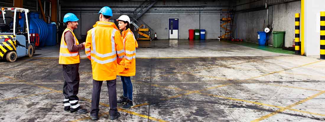 Three workers talking together while standing on a commercial dock. Essential Guide to Your Workers' Compensation Policy. 