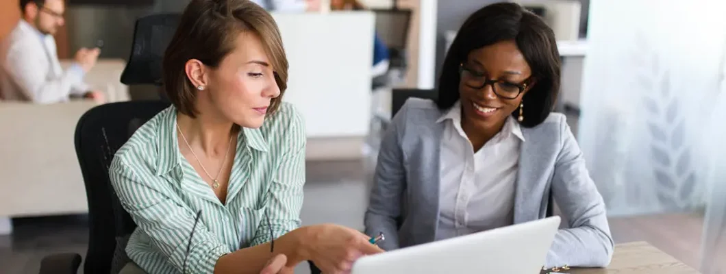 Businesswomen looking at laptop in office. Find Bellaire, Texas business insurance.