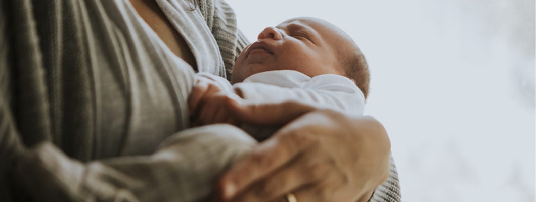 Recovering from childbirth, a mother holds her baby. Individual disability insurance cost.