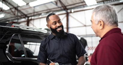 Mechanic man talking to his customer in auto repair. The Truth About Free Car Maintenance Programs.