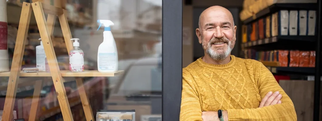 Proud owner standing with arms crossed in front of his store. Find Fairfax, Virginia business insurance.