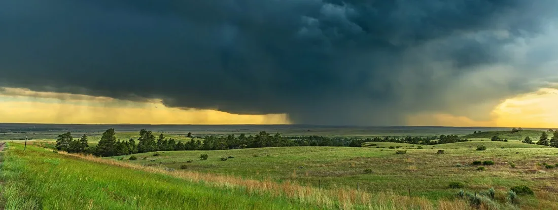 Weather supercell passes over a grassy part of the Great Plains while forming a tornado. Find Tornado Insurance.