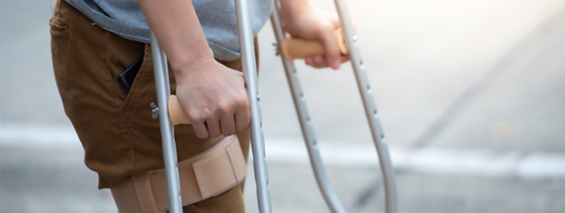 Disabled woman with crutches or walking stick or knee support standing. Find Disability Insurance Programs. 